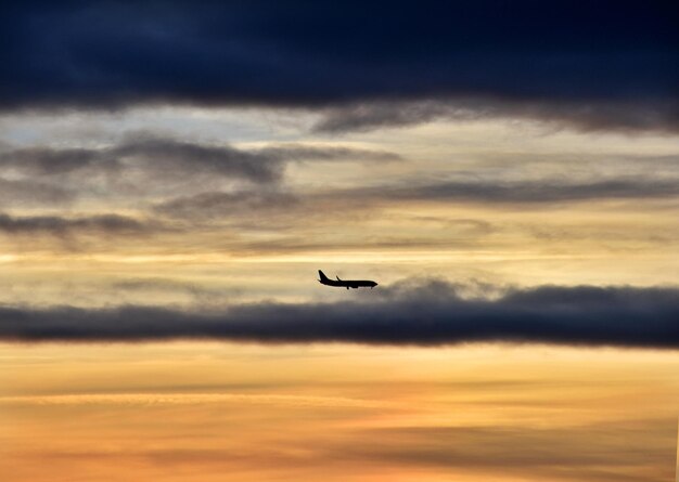 Foto niedrigwinkelansicht eines silhouette-flugzeugs, das im himmel fliegt