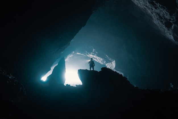 Niedrigwinkelansicht eines Silhouettenmannes, der auf einem Felsen in einer Höhle steht