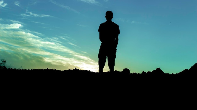 Niedrigwinkelansicht eines Silhouettenmannes, der in der Dämmerung auf dem Feld gegen den Himmel steht