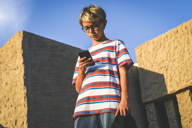 Niedrigwinkelansicht von einem Jungen, der ein Telefon benutzt