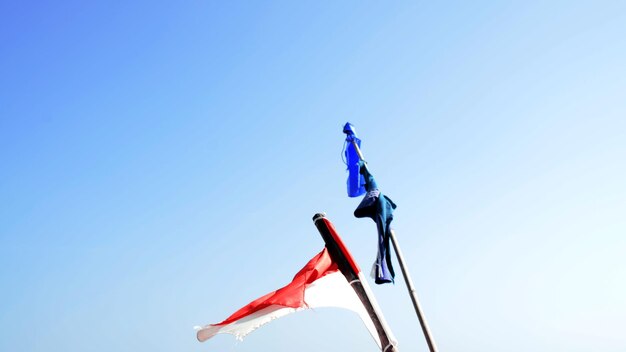 Foto niedrigwinkelansicht von fahnen vor klarem blauen himmel