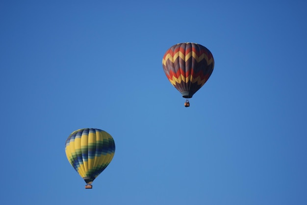 Niedrigwinkelansicht von Heißluftballons, die am klaren blauen Himmel fliegen