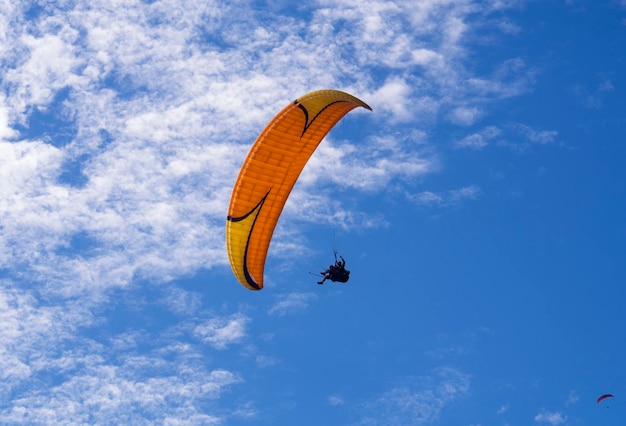 Foto niedrigwinkelansicht von menschen, die gegen den blauen himmel paragliden