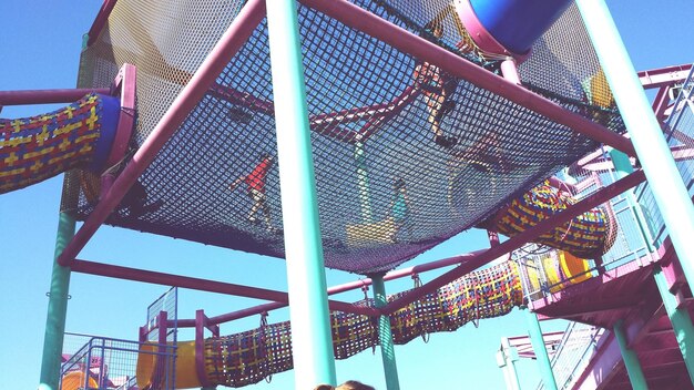 Niedrigwinkelansicht von spielenden Kindern im Dschungel-Gymnasium gegen den Himmel