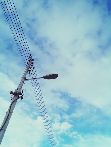 Foto niedrigwinkelansicht von straßenbeleuchtung und kabeln vor bewölktem himmel