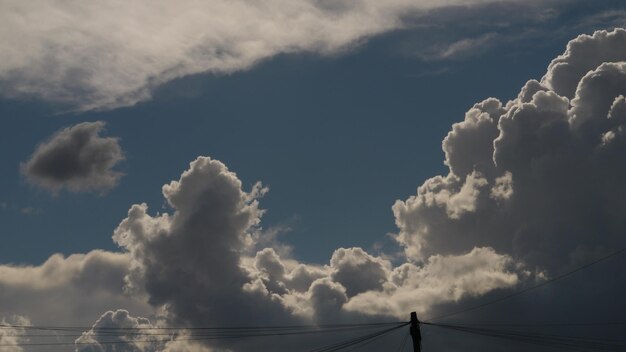 Foto niedrigwinkelansicht von stromleitungen vor bewölktem himmel