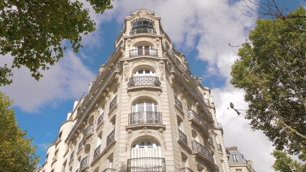 Niedrigwinkelaufnahme des Gebäudes im barocken Architekturstil, Sonne scheint und in den Fenstern reflektiert, nach Blick auf die Herbstbäume. Paris, Frankreich