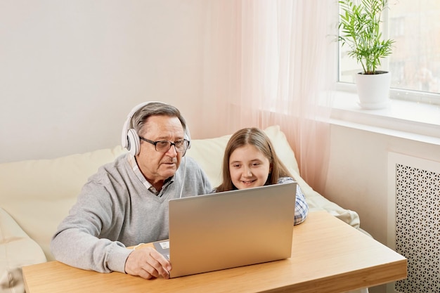 Nieta ayudando al abuelo a comunicarse en línea en una laptop