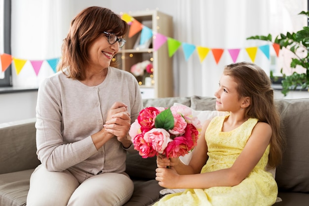 la nieta le da flores a la abuela en casa