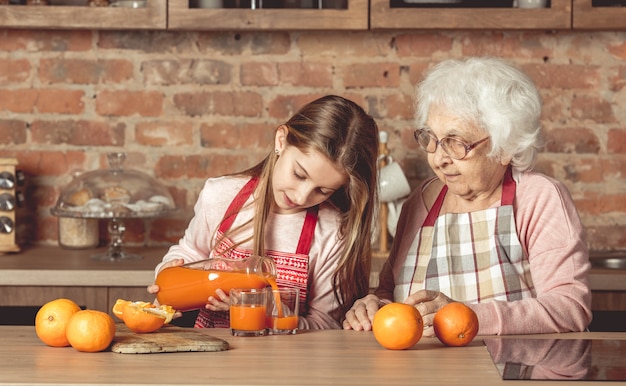 Nieta haciendo jugo de naranja con abuela