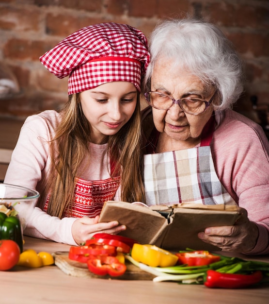 Nieta leyendo libro de recetas con la abuela