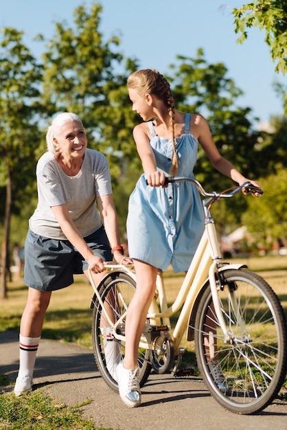 Nieta positiva y su abuela en el parque en bicicleta