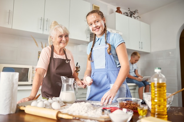 Foto nieta sonriente pasar tiempo en la cocina con una dama senior