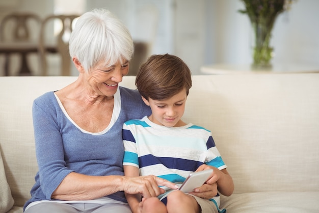 Nieto y abuela con teléfono móvil en la sala de estar