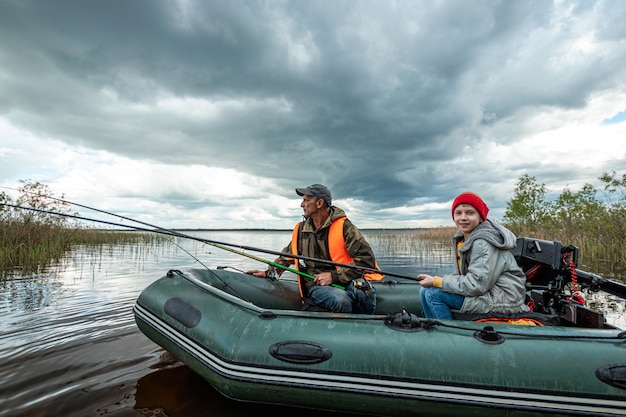 Nieto y abuelo juntos pescan desde un barco en el lago.