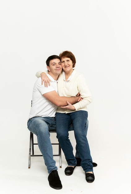 Nieto alegre sostiene a su abuela en sus brazos. familia divertida. nieto adulto con abuela jugando con fondo blanco