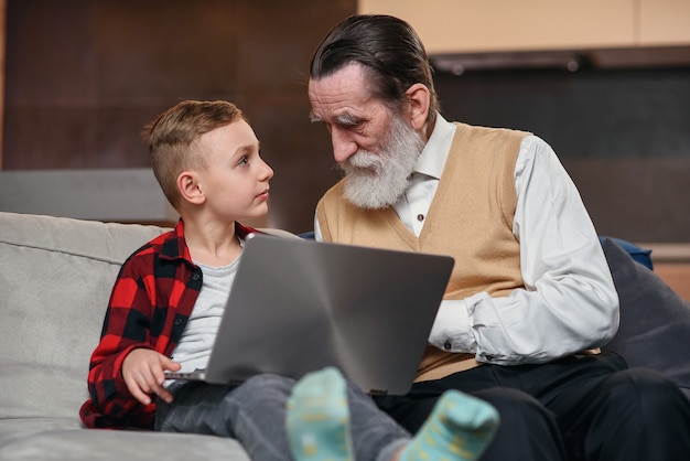 Nieto le está enseñando a su abuelo a usar una computadora portátil.