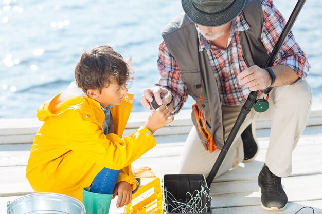 Nieto tomando línea de mar mientras pesca con abuelo