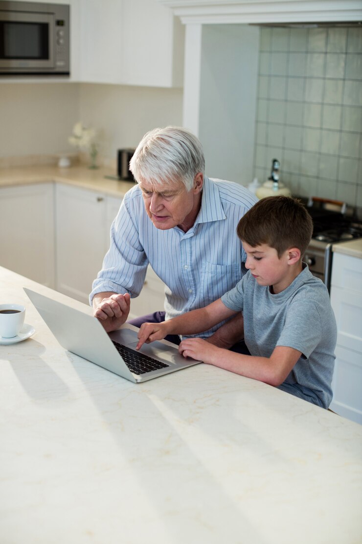 Nieto usando laptop con abuelo