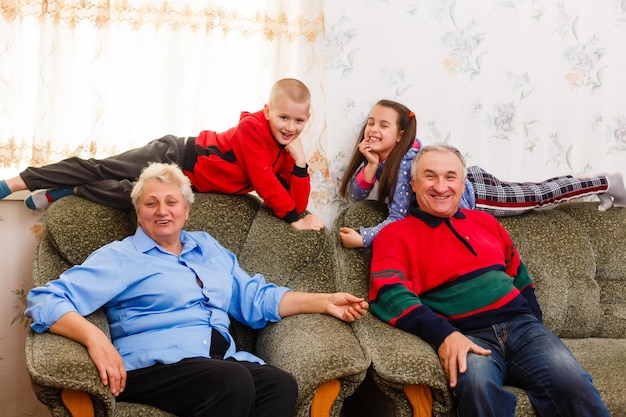 Nietos saltando en el sofá con sus abuelos en la sala de estar