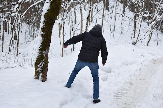 La nieve cae de un árbol en el bosque sobre un hombre. el hombre cae en un camino nevado. el hombre huirá de una avalancha