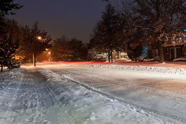 Nieve en la calle y la autopista durante diciembre de 2016 tormenta de invierno de carretera helada en zona urbana por la noche