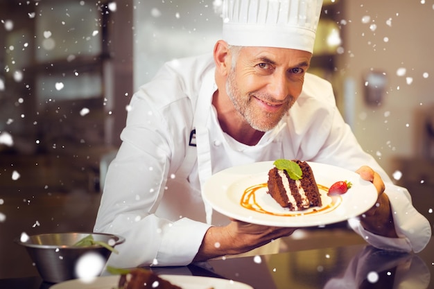 Foto nieve contra el chef pastelero masculino sonriente con postre en la cocina