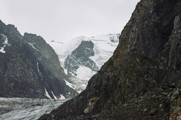 Nieve en la cordillera. Cresta nevada atmosférica debajo del cielo nublado. Maravillosas rocas gigantes en tiempo nublado. Sube alto en las montañas. Increíble paisaje minimalista de majestuosa naturaleza de las tierras altas.