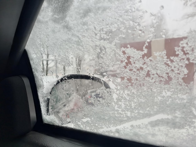 Nieve en el cristal lateral y vista desde el interior del coche