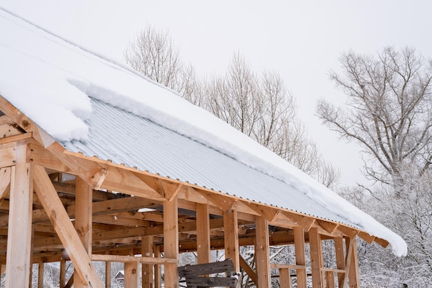 Nieve deslizándose desde el techo de la casa de construcción con techo de metal cubierto de nieve congelada fresca y copos de nieve en el día de invierno helado en el suburbio de la aldea rural temporada de invierno nevado clima frío