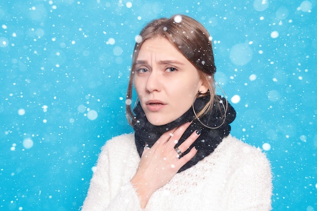 Nieve, invierno, navidad, enfermedad, salud, personas, concepto de medicina - dolor de garganta. Primer plano de una mujer enferma con dolor de garganta que se siente mal. Hermosa chica tocando el cuello con la mano sobre fondo de nieve