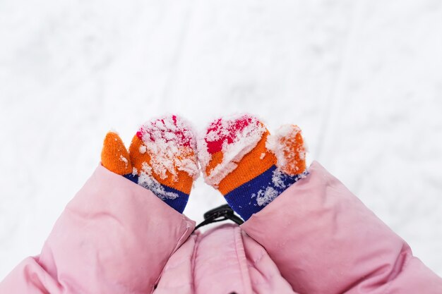 Nieve en mitones o guantes. Las manos de los niños están tomados de la mano en la nieve.