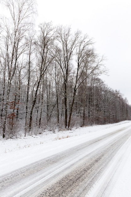 Nieve sucia que cubre la carretera con asfalto, primer plano de la foto en invierno