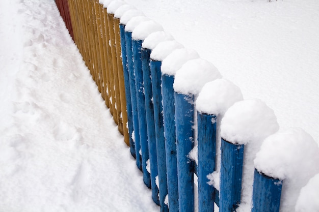 Nieve en una valla de madera. Valla de madera rústica cubierta de nieve.