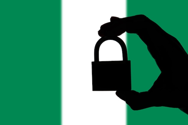 Nigeria seguridad Silueta de mano sosteniendo un candado sobre bandera nacional