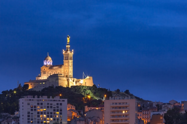 Foto night old port e a basílica de notre dame de la garde ao fundo, na colina, marselha, frança