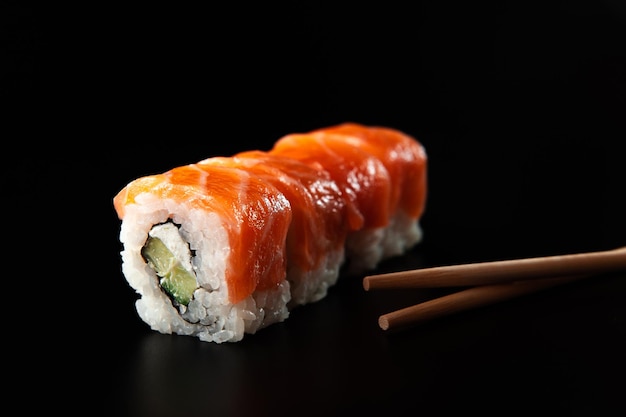Nigiri de sushi de salmón en palillos sobre fondo negro