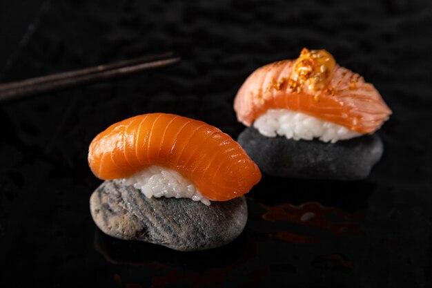 Nigiri sushi con salmón sobre piedras y plato brillante