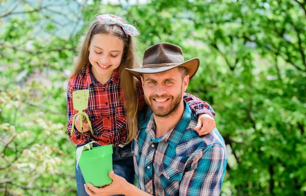 Nimm deine Blume, kleines Mädchen und glücklicher Mann, Papa, Tag der Erde, neues Leben, Familie, Bauernhof, Landwirtschaft, Frühling, Dorf, Land, Vater und Tochter auf der Ranch, Ökologie, Umwelt, Böden und Düngemittel