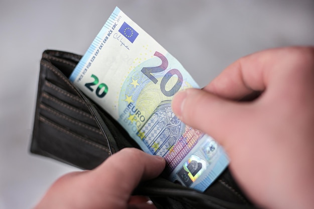 Nimmt einen 20-Euro-Schein heraus oder steckt ihn in eine Brieftasche auf hellem Hintergrund