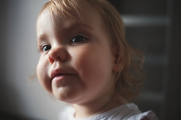 Una niña de 1,5 años está de pie y sonriendo. El niño baila y camina. Chica alegre en el apartamento