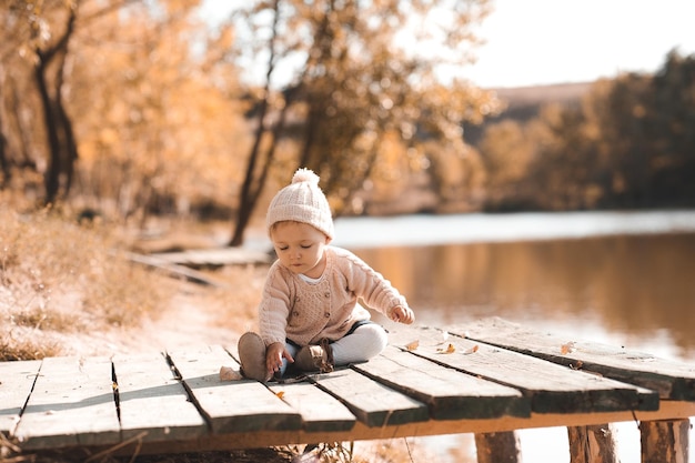 Niña de 1 año jugando en el parque de otoño Vistiendo ropa de punto de moda al aire libre