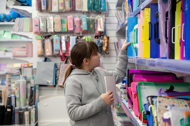 Niña de 12 años eligiendo cuadernos en papelería xDxA