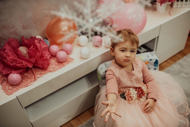 niña de 2 años con vestido rosa con su primer pastel de cumpleaños feliz cumpleaños carda linda niña celebra su primer cumpleaños rodeada de regalos