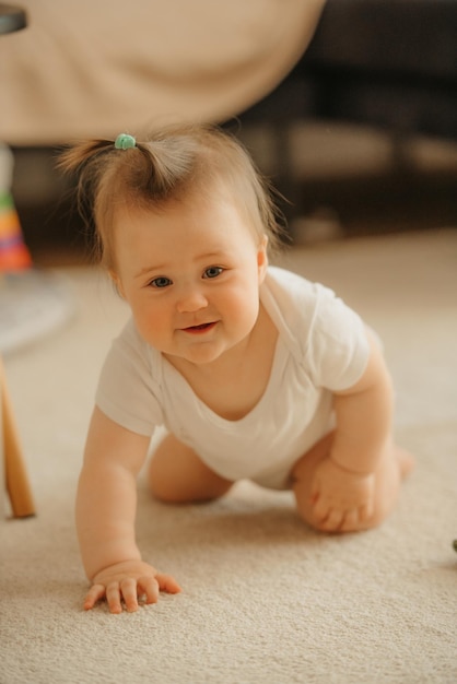 Una niña de 7 meses está sentada cerca de un sofá y haciendo muecas en un mono en casa