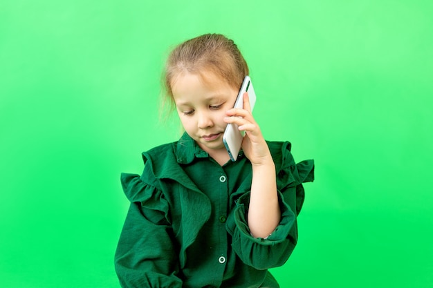 Una niña de 8 años está sentada hablando por teléfono.