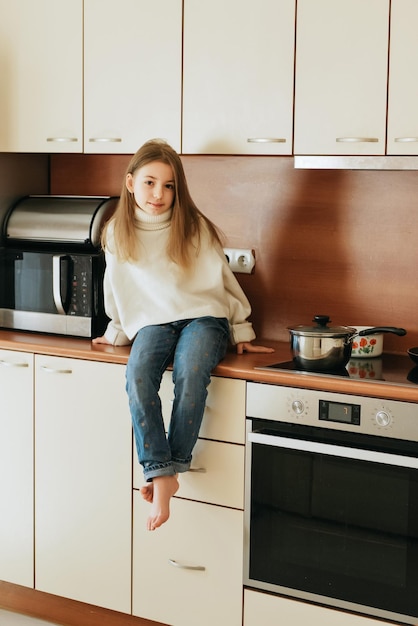 niña de 9 años con cabello largo modelo colegiala en casa estilo de vida en una cocina beige