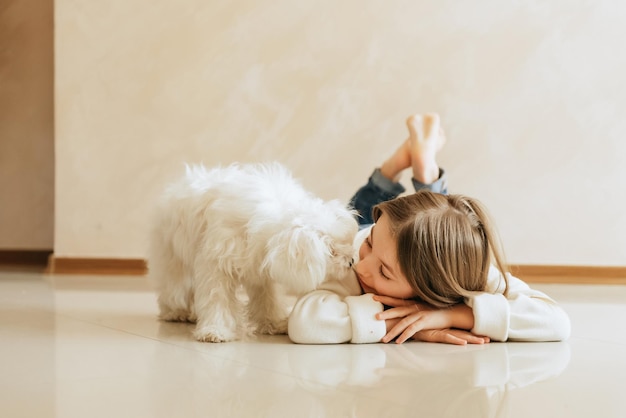 niña de 9 años con modelo de cabello largo con un perro mascota Colegiala maltesa en el estilo de vida del hogar