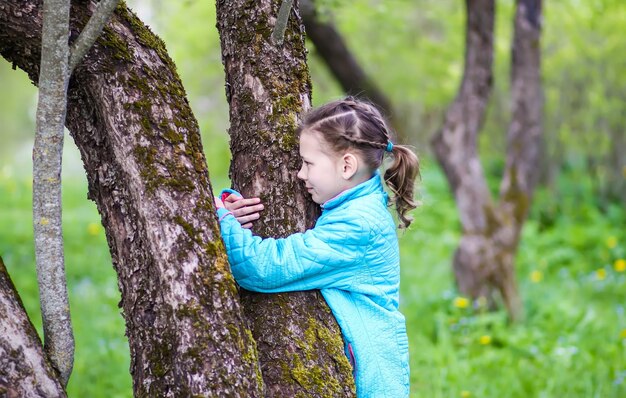 Una niña abraza un árbol