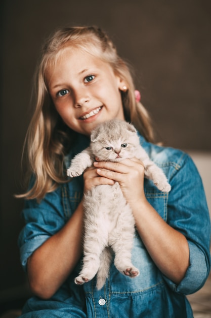 Niña abraza a un gatito británico